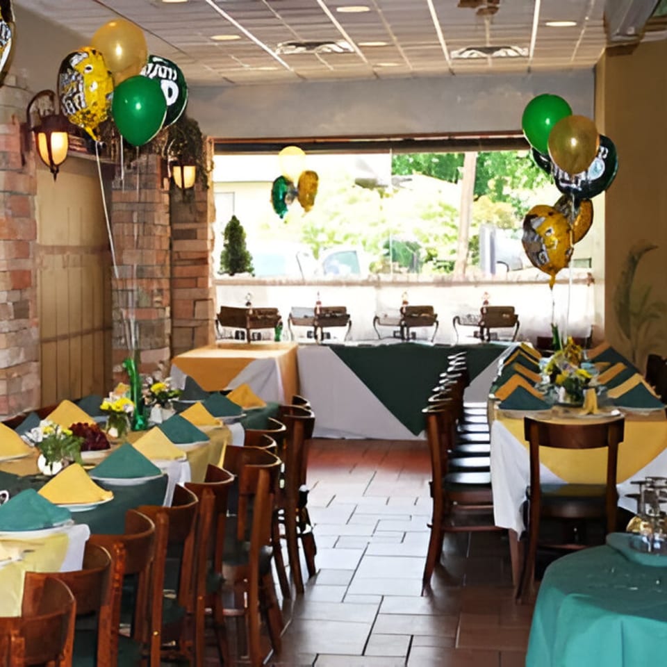 A Cousins Pizza dining room set for a party with green and yellow balloons, tablecloths, and napkins.